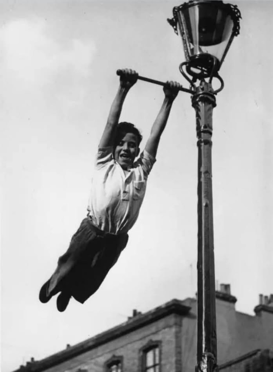 Подтягивание на фонаре. Сейчас таких фонарей с палочкой для флагов уже нет. Видимо, убрали именно из-за детей. Фотография из открытого источника. 