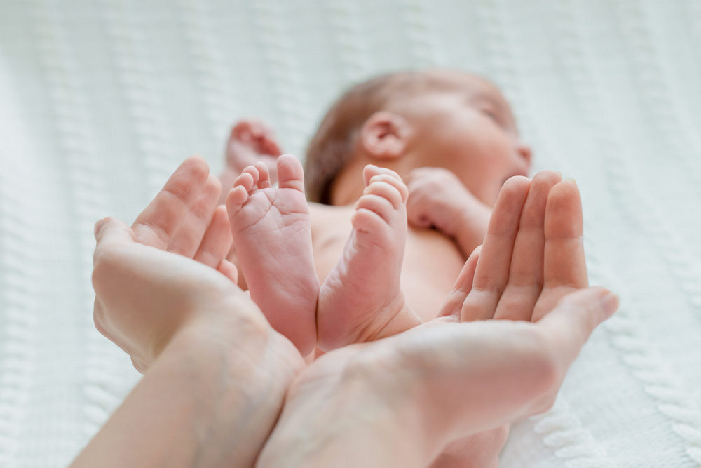    Baby feet in woman hands. Mom and her Child. Happy Family concept Админ