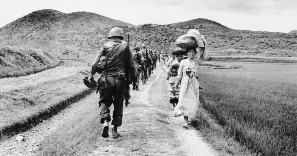 Американские солдаты проходят мимо беженцев во время Корейской войны 1950-1953.