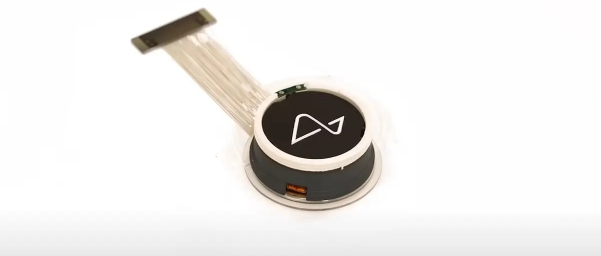 Крупный план чипа-импланта Neuralink для интерфейса мозг-компьютер, с подключенным ленточным кабелем для передачи данных.