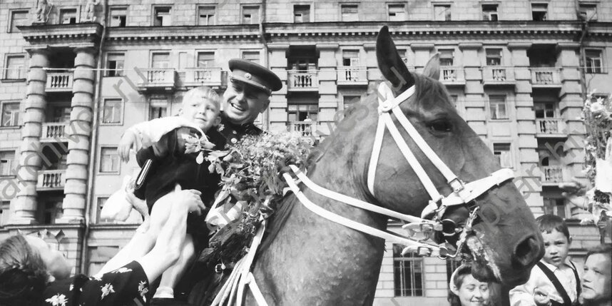    Герой Советского Союза генерал-майор А.Ф. Щеглов сажает на своего коня мальчика, подарившего ему букет цветов. 8 июля 1945г. Ленинград. Автор съемки: Чертов Г.И.пресс-служба Музея Фаберже