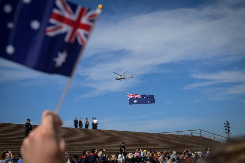 Над Сиднейским оперным театром виден вертолет с австралийским национальным флагом. [Фото Джорджа Чана/SOPA Images/LightRocket через Getty Images]