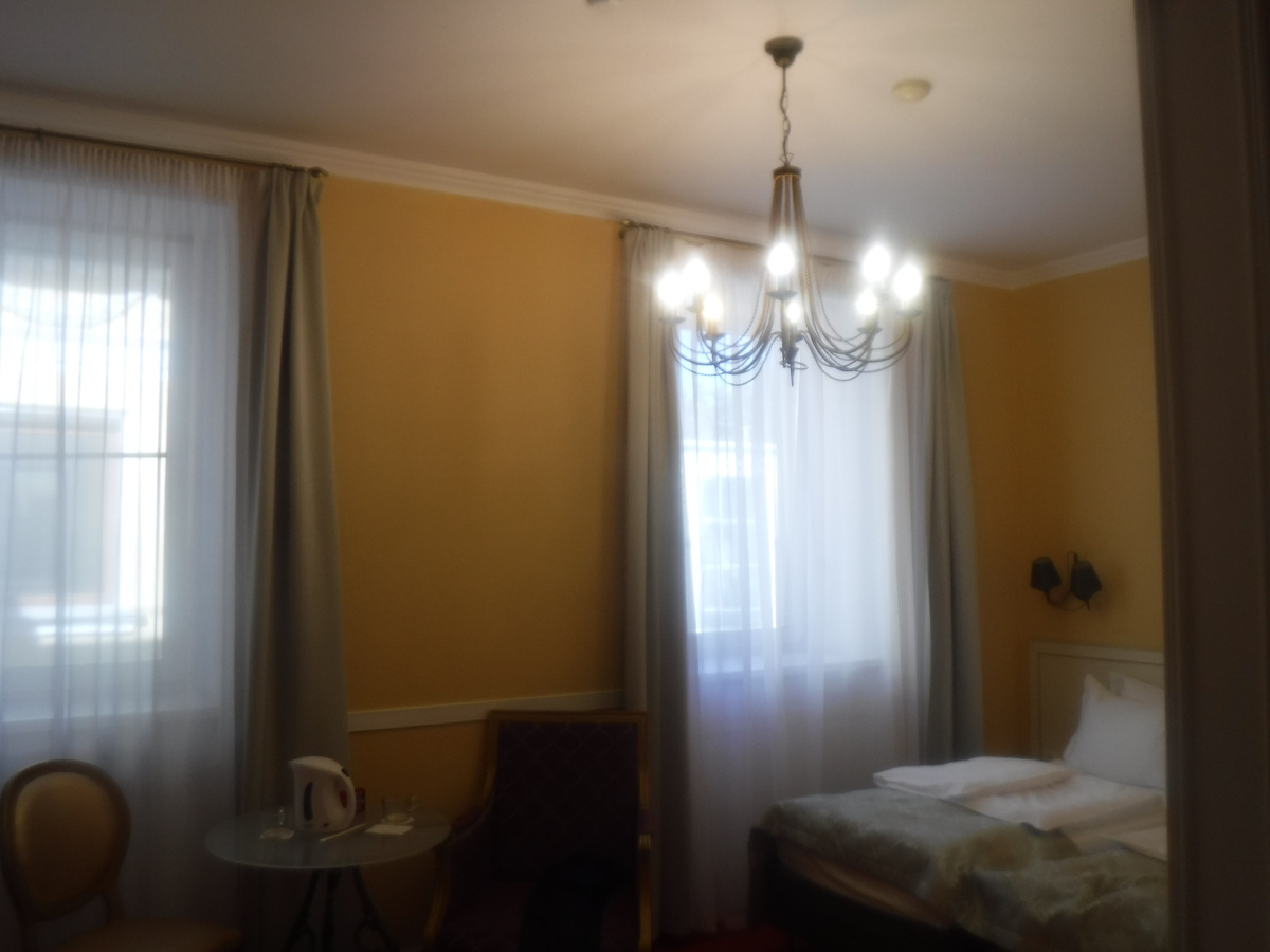 В номере. Здесь есть люстра и, две кровати и стекляный столик с креслом и стулом