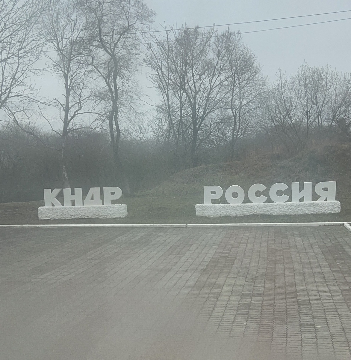 Окно поезда мутное. Вот такие бетонные буквы можно наблюдать из окна. Слово "Россия" переделано из СССР с добавлением новых букв