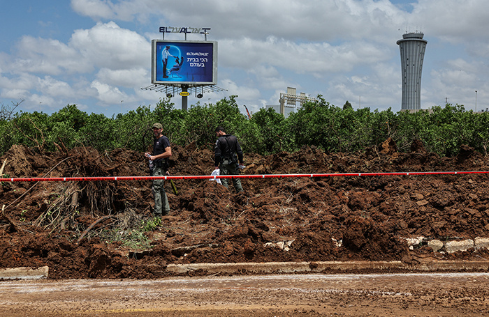    Израильские полицейские на месте ракетного удара недалеко от аэропорта Бен-Гурион в Тель-Авиве.REUTERS/Nir Elias