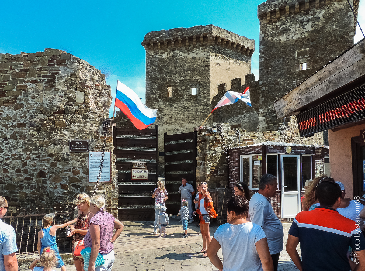 Перед воротами барбакана. На них развевают флаги Генуи и правящего дожа. Третьего традиционного флага консула с гербом не хватает. Запомните, флагов и гербов здесь всегда должно быть три и они должны выражать лояльность Генуе и Кафе. В крайнем случае банку Святого Георгия.