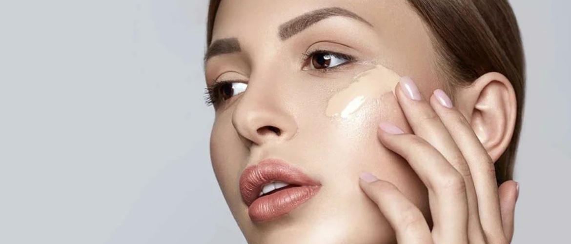 Женщина наносит тональный крем на лицо