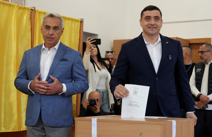    Кэлин Джорджеску и Джордже Симион во время первого тура президентских выборов, 4 мая 2025 года.Reuters/Louisa Gouliamaki