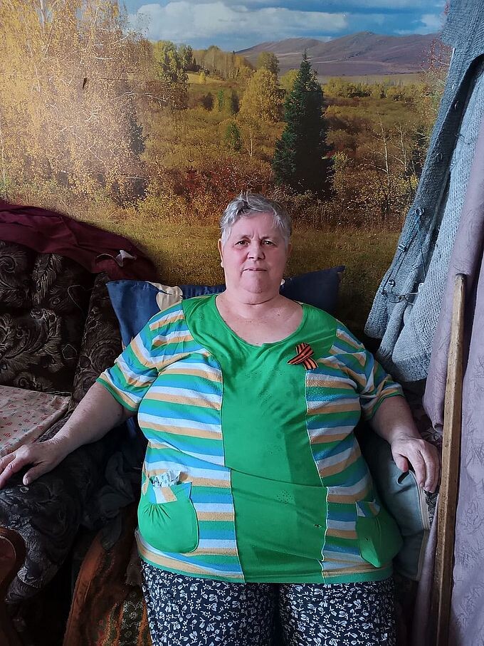 Пожилая женщина с прикреплённой на груди Георгиевской ленточкой