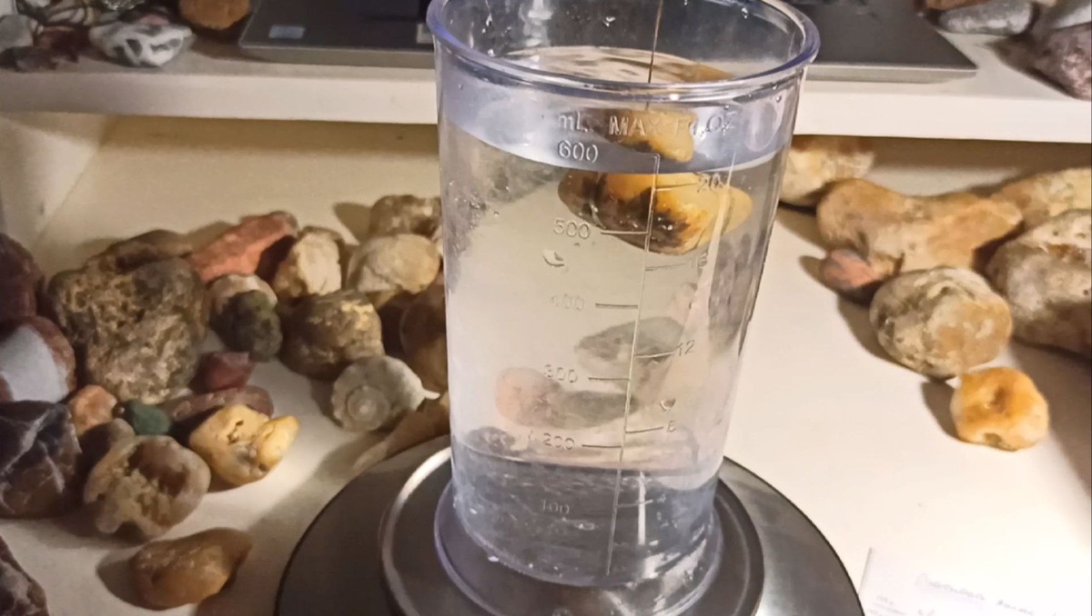 Камень погружается в воду на верёвочке, не касаясь стенок и дна ёмкости.