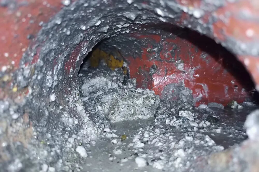 Это гипсовые отложения в канализационной трубе. Здесь почти половина трубы уже забита гипсом