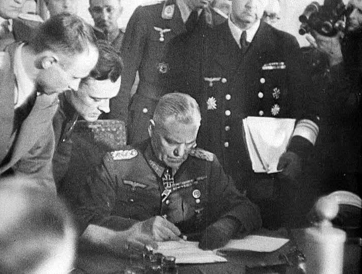 Кейтель подписывает акт о безоговорочной капитуляции Германии, слева наклонился и "контролирует" процесс подписания Александр Коротков