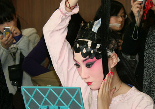 Актриса накладывает грим амплуа дань с контрастными чёрными полосками тепяньцзы