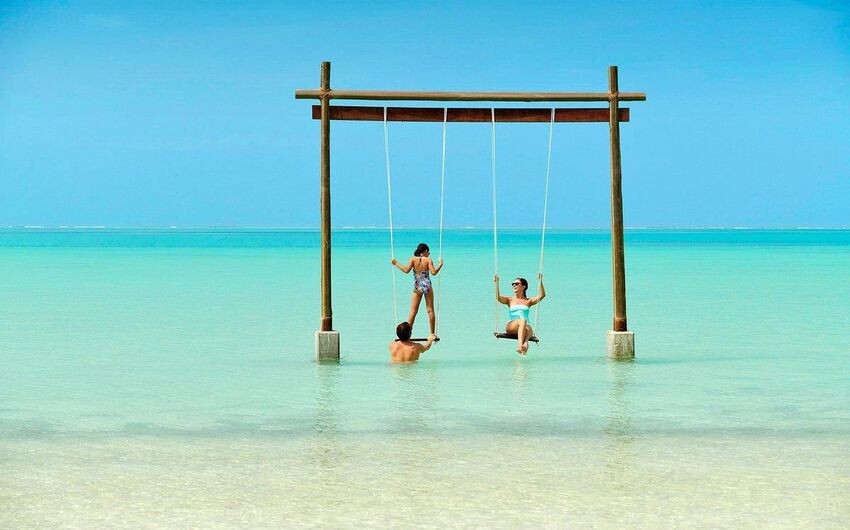 
Покачайтесь на качелях на побережье над бирюзовой водой