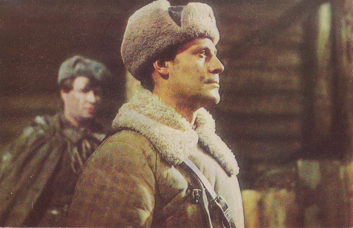 Открытка иллюстрированная. Кадр из фильма «Блокада». Кадр из фильма-эпопеи «Блокада» по одноименному роману Александра Чаковского. На переднем плане – актёр Юрий Соломин в роли майора Звягинцева, на заднем плане – актёр Иван Краско в роли старшего лейтенанта Горелова. На оборотной стороне: отсутствует почтовое графление, в правом верхнем углу предупреждающая надпись, ниже краткая информация о создателях фильма, выдержка из речи М.И. Калинина, произнесённой 26 января 1945 года – во время вручения ордена Ленина городу Ленинграду за выдающиеся заслуги трудящихся Ленинграда перед Родиной в годы Великой Отечественной войны советского народа