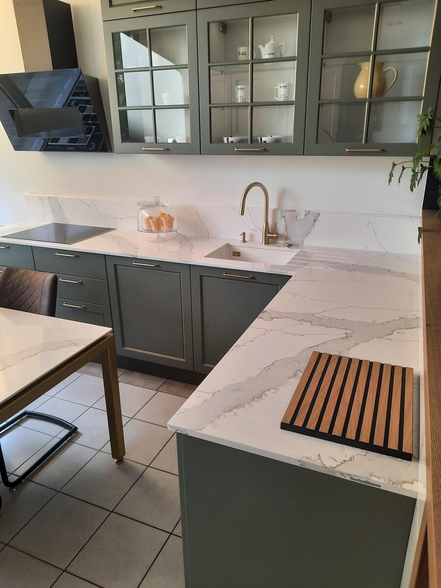 Белая столешница из кварца Calacatta Volegno TechniStone с мраморными прожилками на зеленой кухне