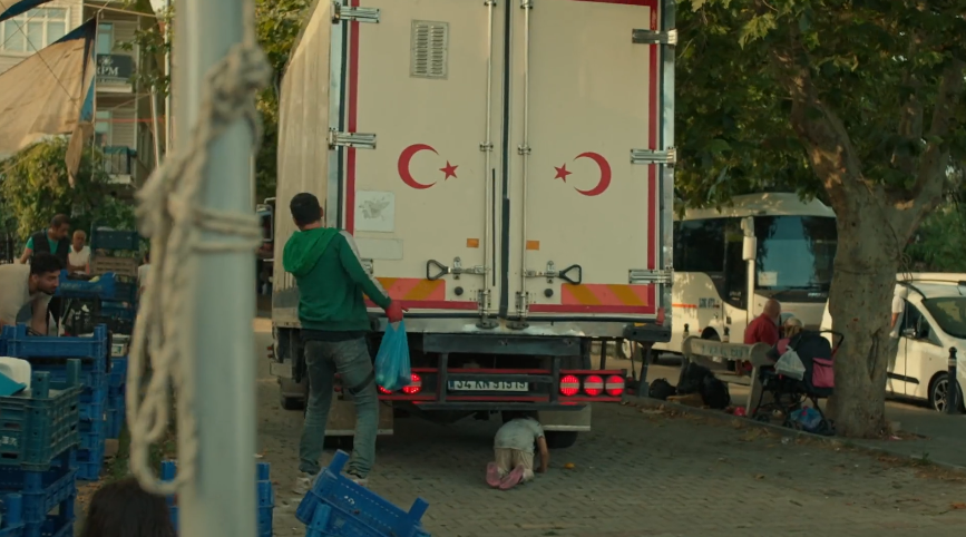 Кадр из сериала. Девочка-беспризоница лезет под машину за спелым яблоком, а Яман спасает