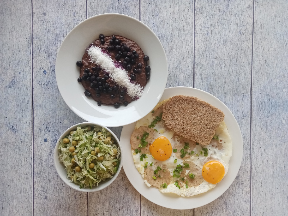 Завтрак. Шоколадная овсянка с ягодами и кокосовой стружкой, яичница с колбасой, хлеб и салат.