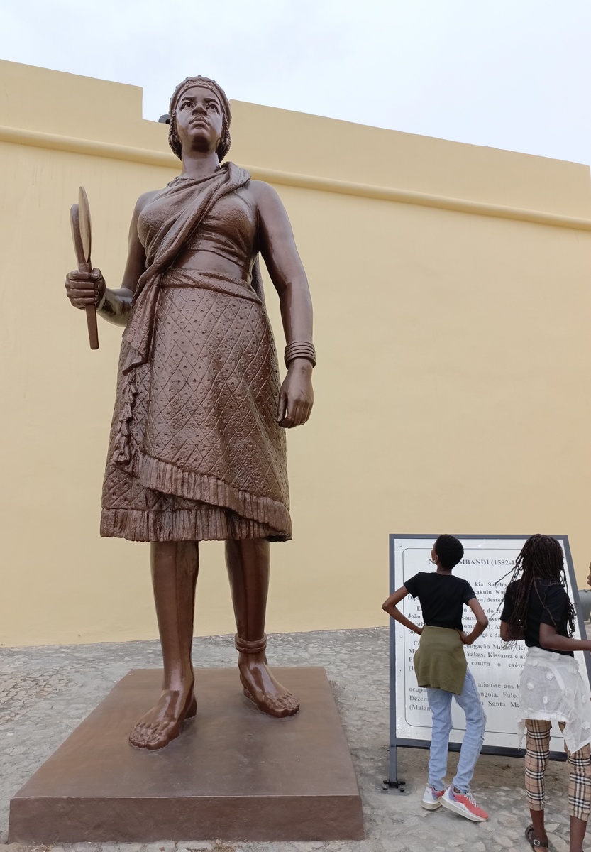 Жинга – королева Ндонго (1581- 1663). Она правила своей страной целых 40 лет, а прожила аж 82 года. В Анголе ее весьма почитают. Еще будучи принцессой, она прибыла на переговоры с португальцами, и обнаружив, что ей не предоставили стул (явный знак неуважения со стороны европейцев), она не топнула ногой, не покинула переговоры и не обиделась, а приказала одному из своих слуг принять позу стула и воссела не него, чем сразила наповал португальцев. Фото сделано в историческом музее в Луанде. 