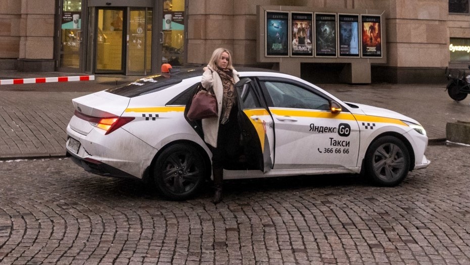    Молодая женщина выходит из машины такси в Петербурге. Автор фото: Михаил Тихонов / "Деловой Петербург"