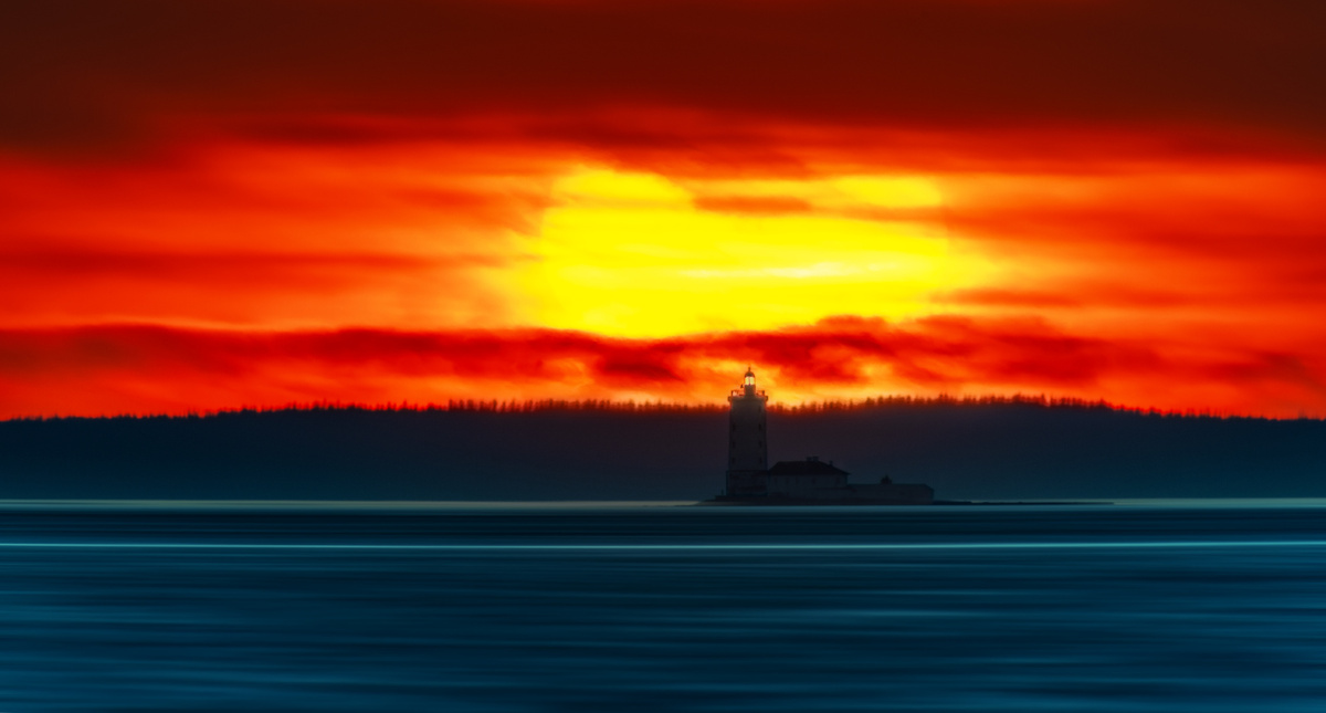 На западном горизонте яркий солнечный закат на фоне маяка Толбухин. Кронштадт, 12.05.2025