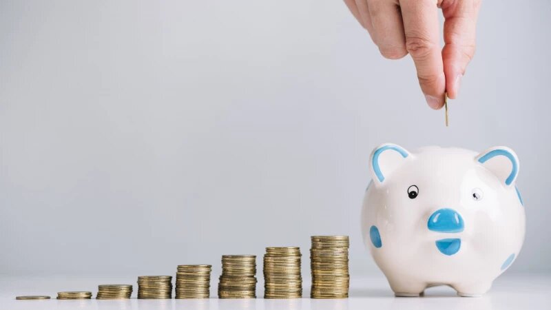     Столбики монет, мужчина кладёт монету в копилку. Фото: ru.freepik.com, автор freepik.