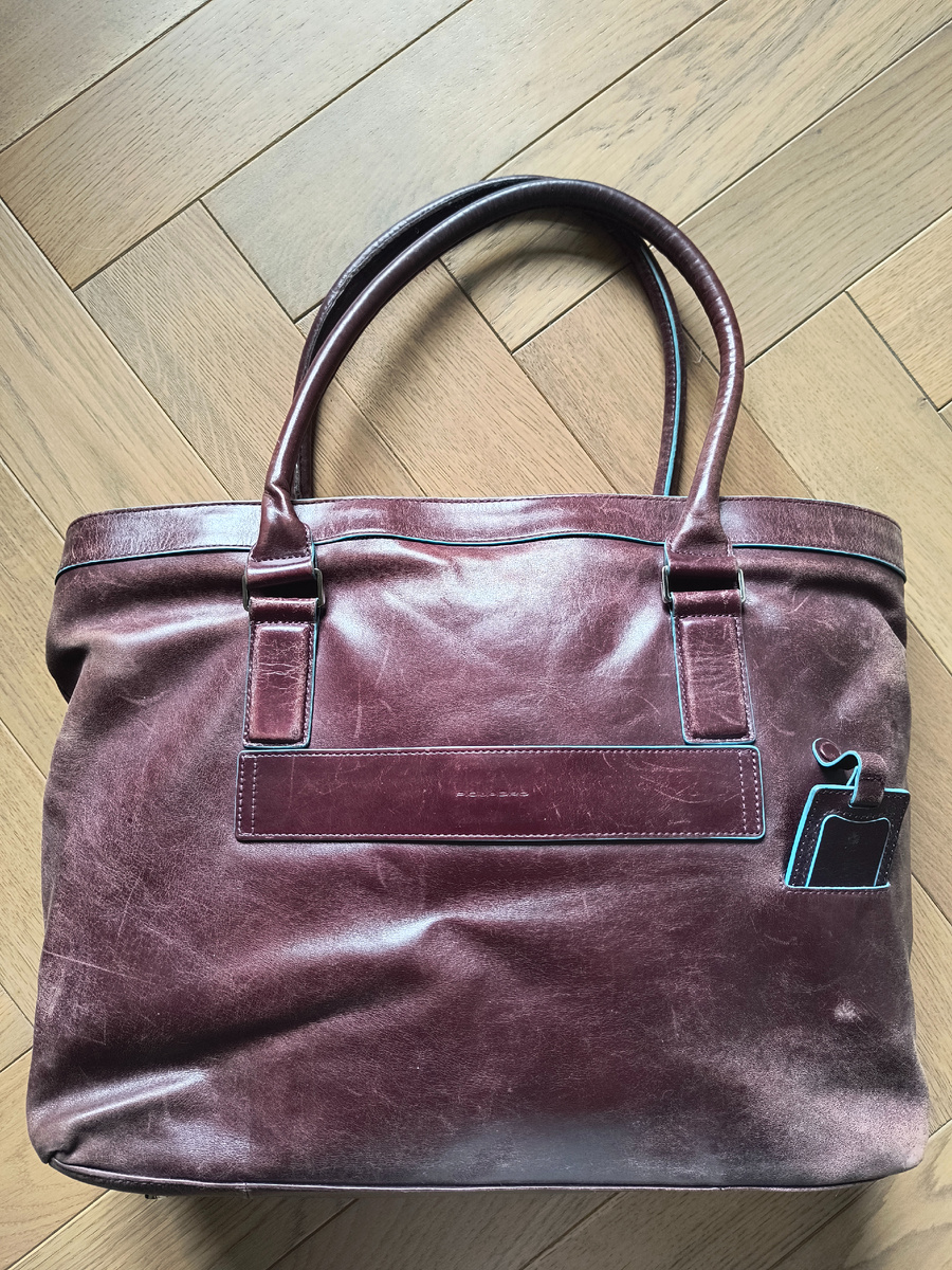 Любимый Piquadro. Убила примерно за 3 года своих бесконечных поездок. Влезает абсолютно все. Как оказалось -синие полоски и пигмент очень быстро вытираются. Лежит в шкафу, не пользуюсь, но выкинуть не могу. Жалко. Иногда достаю как винтаж. Если сама в новых хороших вещах, сумка выглядит как "потёртости специально задуманы".