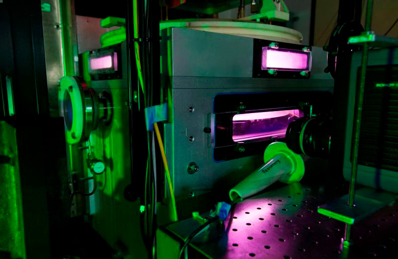 Фиолетовое свечение плазмы видно внутри модифицированной машины плазменного травления Lam Research в Базовом плазменном научном центре Калифорнийского университета в Лос-Анджелесе.