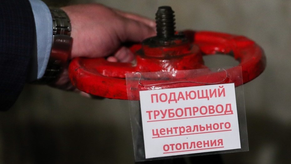   Мужчина перекрывает подающий трубопровод центрального отопления. Автор фото: Донат Сорокин / ТАСС
