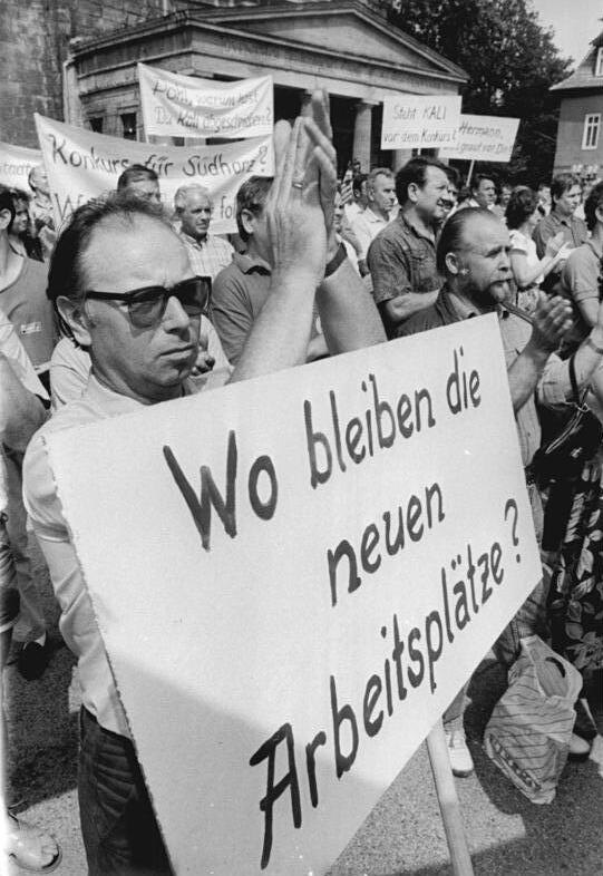 Демонстрация в Зондерсхаузене против закрытия местного предприятия по добыче калия, июль 1990 года. На плакате написано: «Где остаются новые рабочие места?» Авторство: Bundesarchiv, Bild 183-1990-0721-006 / Hirschberger, Ralph / CC-BY-SA 3.0, CC BY-SA 3.0 de, https://commons.wikimedia.org/w/index.php?curid=5425723