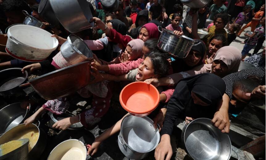 Палестинцы ждут еду приготовленную на благотворительной кухне, в Джабалии, на севере сектора Газа, 19 мая 2025 года. REUTERS/Махмуд Исса