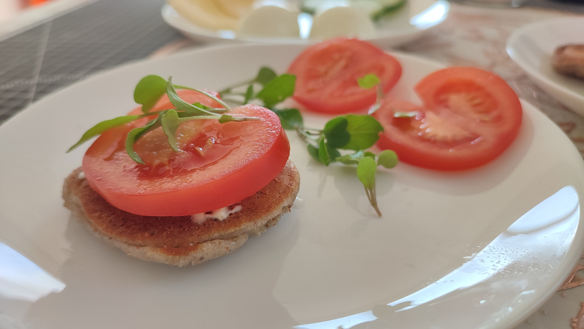 Бутерброд: оладушка из зелёной гречки, капля майонеза, помидор, руккола, соль и красный перец