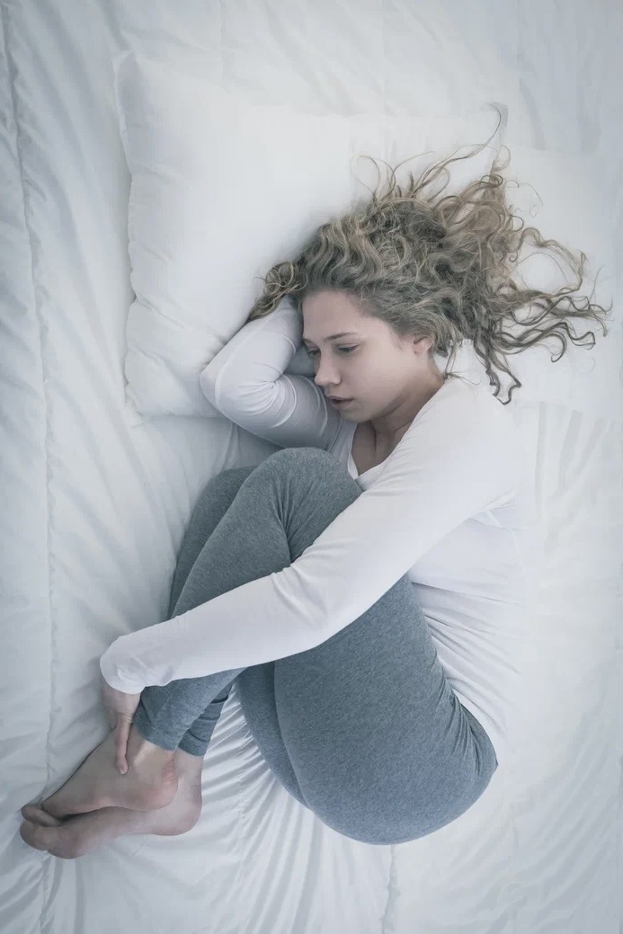 Вы лежите на боку, подтянув колени к груди, иногда обнимаете подушку.  