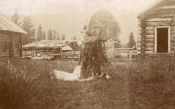 Алтайский шаман с поднятым вверх бубном 
на фоне жилища в селе Абай на Алтае, 1895 год