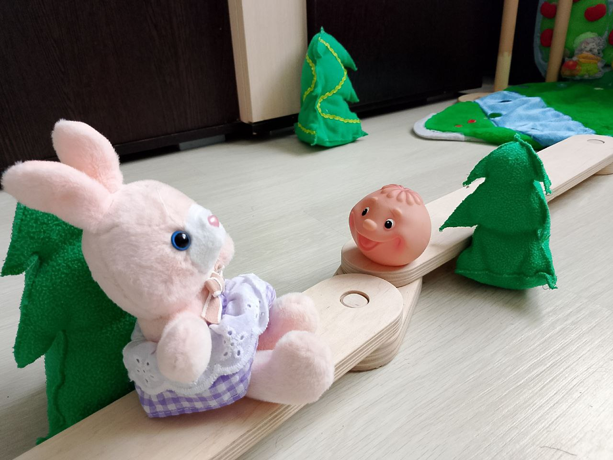 Ребёнок катит мячик-колобок по дорожке-балансиру.