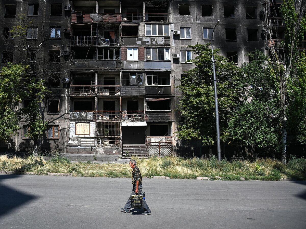    Мужчина проходит мимо жилого дома, разрушенного в результате боевых действий в Мариуполе© РИА Новости /
