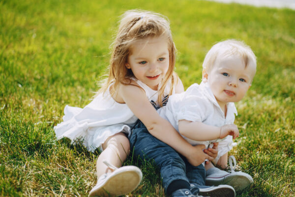    A little beautiful girl sits in a grassy park with her sweet younger brother Новостная служба "Правмир"