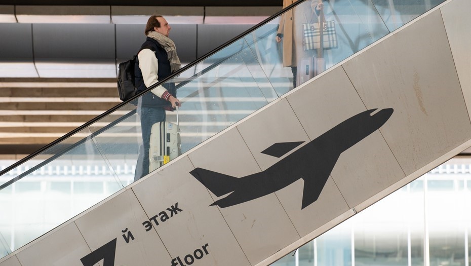    Мужчина с чемоданом поднимается по эскалатору ко входу в здание аэропорта Пулково в Петербурге. Автор фото: Сергей Ермохин / "Деловой Петербург"