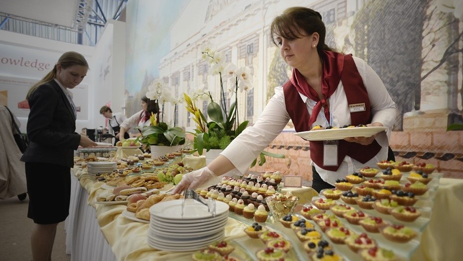    Сотрудница кейтеринговой компании помогает разложить блюда на тарелки участников ПМЭФ Автор фото: Валентина Свистунова / "Деловой Петербург"
