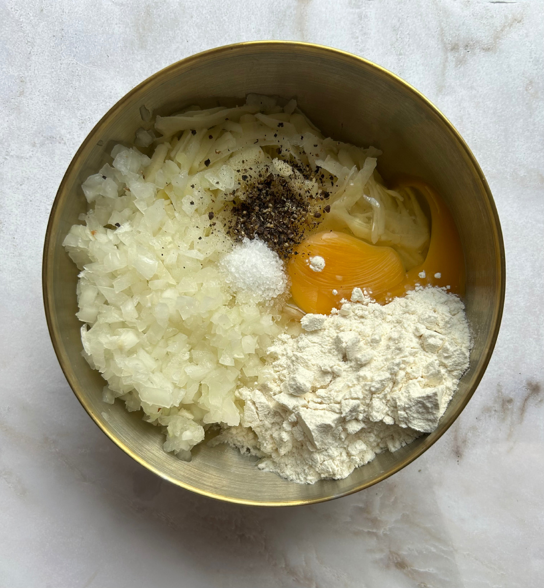 Слить воду и к тертому картофелю добавить мелко нарезанный лук;муку,яйцо,соль и специи;всё смешать.
