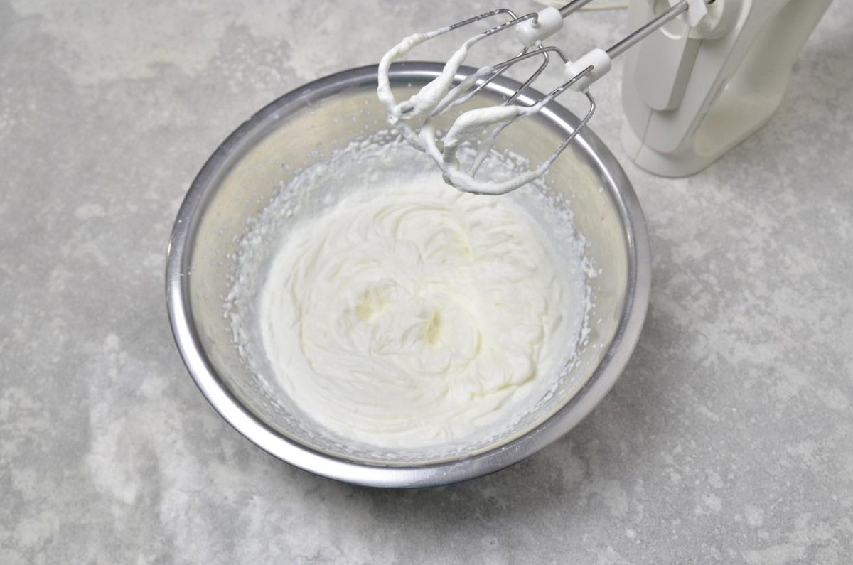 Влейте холодные сливки в глубокую миску. Начните взбивать их миксером на небольших оборотах — пока сливки жидкие, они будут брызгаться. Затем, по мере того, как сливки будут становиться гуще, скорость прибавьте. Взбивайте сливки до мягких пиков — венчики миксера будут оставлять явный след. Главное поймать этот момент и не перевзбить их — это когда сливки пойдут хлопьями и отделится сыворотка (получится масло).
