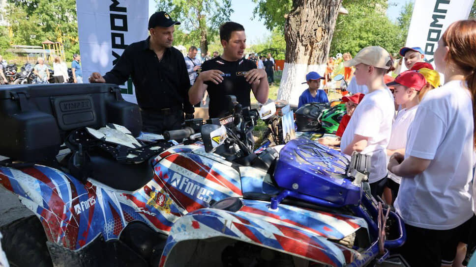Полпред в УрФО Артем Жога (слева) и гонщик Артем Карякин (второй слева) показывают детям квадроциклы.📷Фото: Telegram-канал полпреда в УрФО Артема Жоги