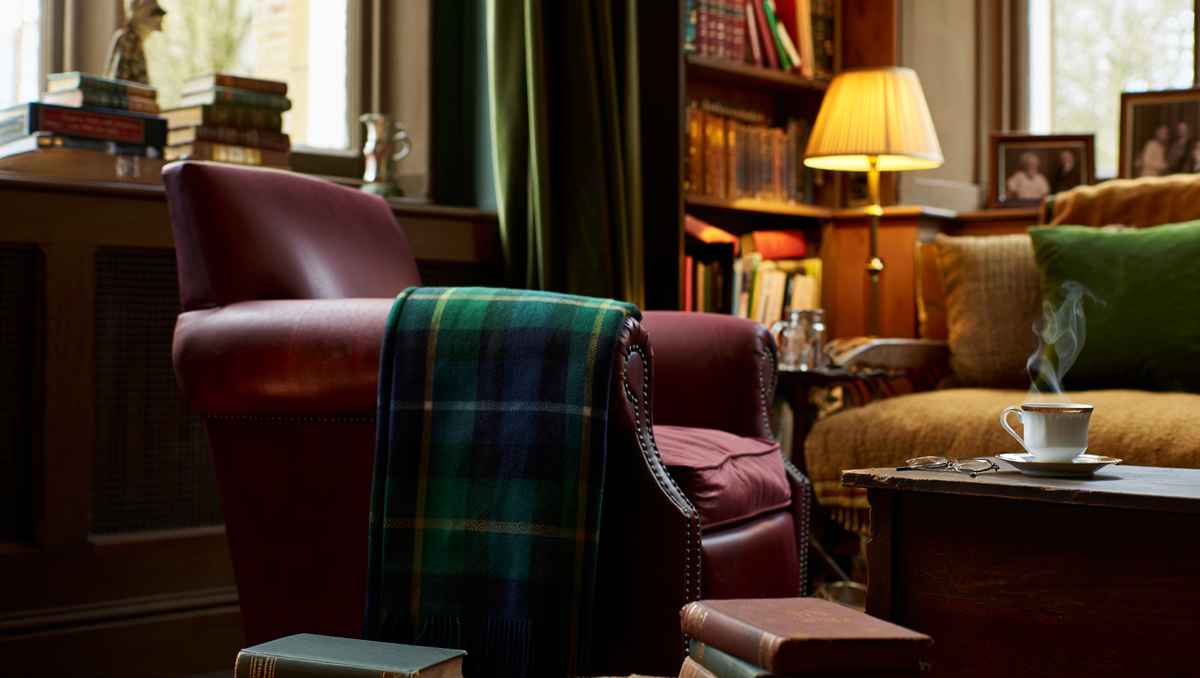 Уютная гостиная в британском стиле — естественный свет, выразительная фактура тканей, винтажное кресло с клетчатым пледом, книги и детали личной истории, атмосфера жизни и уюта.