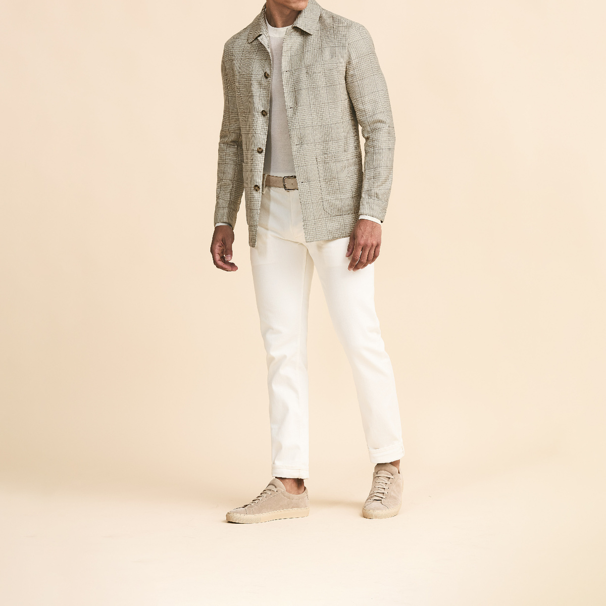 Пиджак песочного цвета в серую клетку из шерсти, шелка и льна, джемпер с круглым вырезом, брюки 5 карманов и сникеры светло-бежевого цвета из натуральной замши.