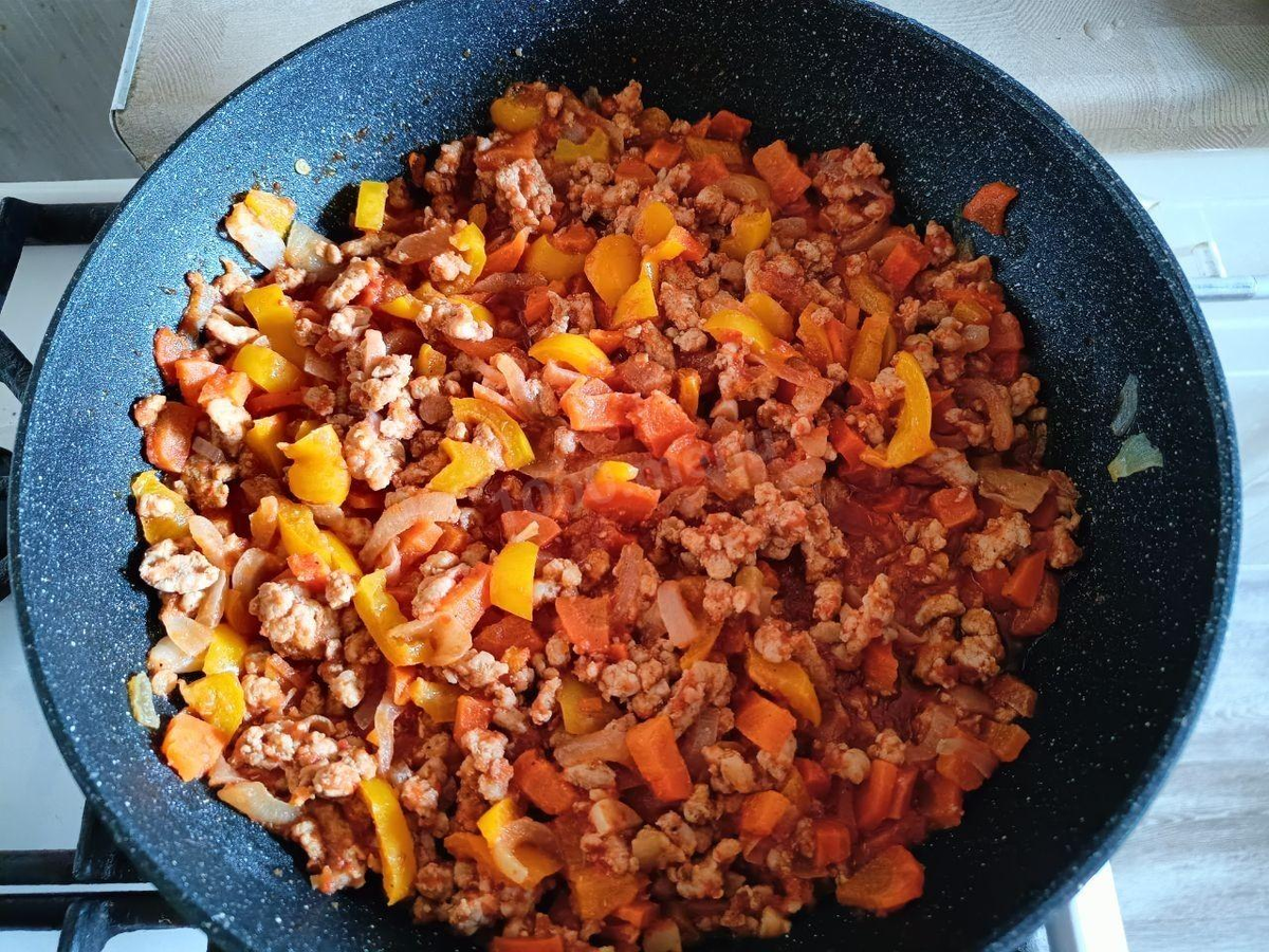 Нарежьте лук кубиком и обжарьте его в сковороде на растительном масле до мягкости. Морковь и болгарский перец нарежьте кубиком и отправьте к луку. Обжарьте всё вместе 3-5 минут. Затем выложите на сковороду фарш, перемешайте, разбивая комочки фарша, и жарьте 5-7 минут до готовности фарша. Добавьте соль и перец по вкусу и мелко нарезанный чеснок. Влейте томатный сок или томатную пасту. Тушите на сильном огне около 5 минут, чтобы выпарилась лишняя жидкость.\