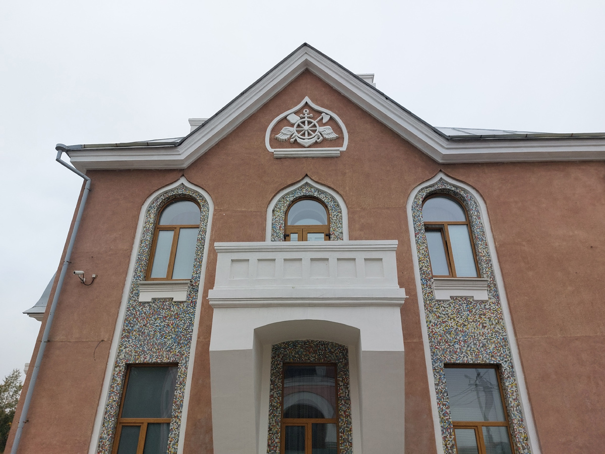 Мозаика, лепнина, кованные решетки с узором на крыше, форма окон заметно оживляют облик здания и оно уже смотрится довольно привлекательно.