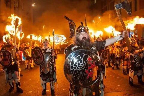 группа людей в старинных одеждах несёт горящий факел 