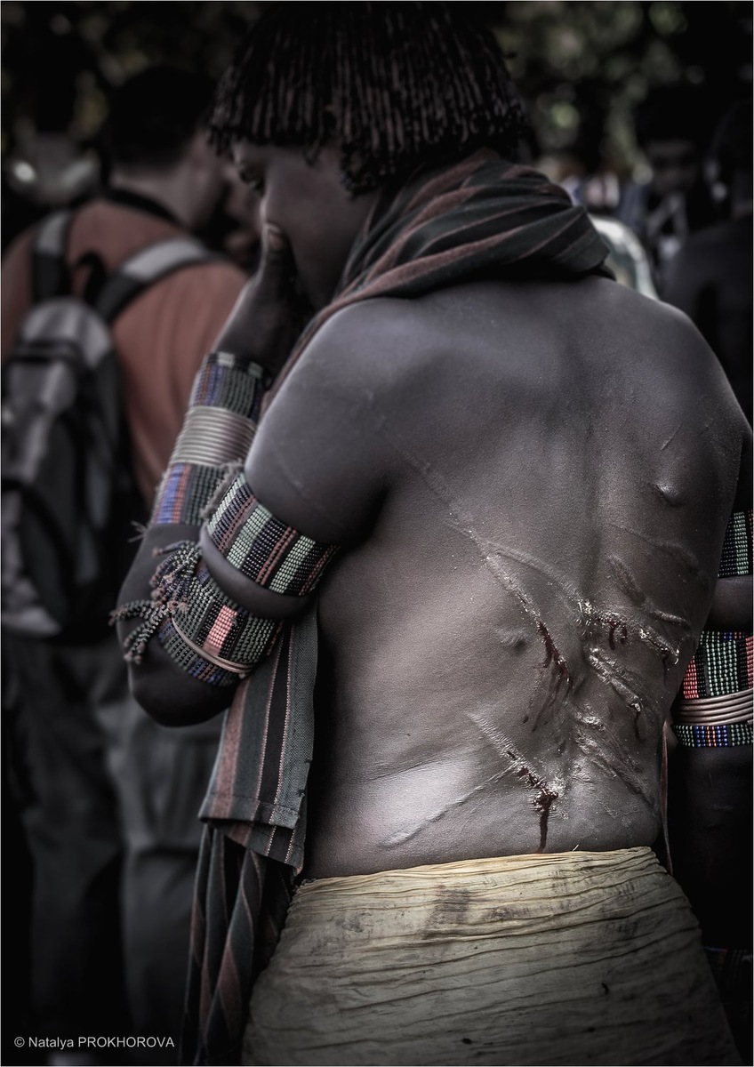 Женщины в традиционных украшениях племени хамар стоят рядом с женихом, их спины покрыты шрамами от ударов плетью. Они смотрят с гордостью и решимостью. фото из интернета