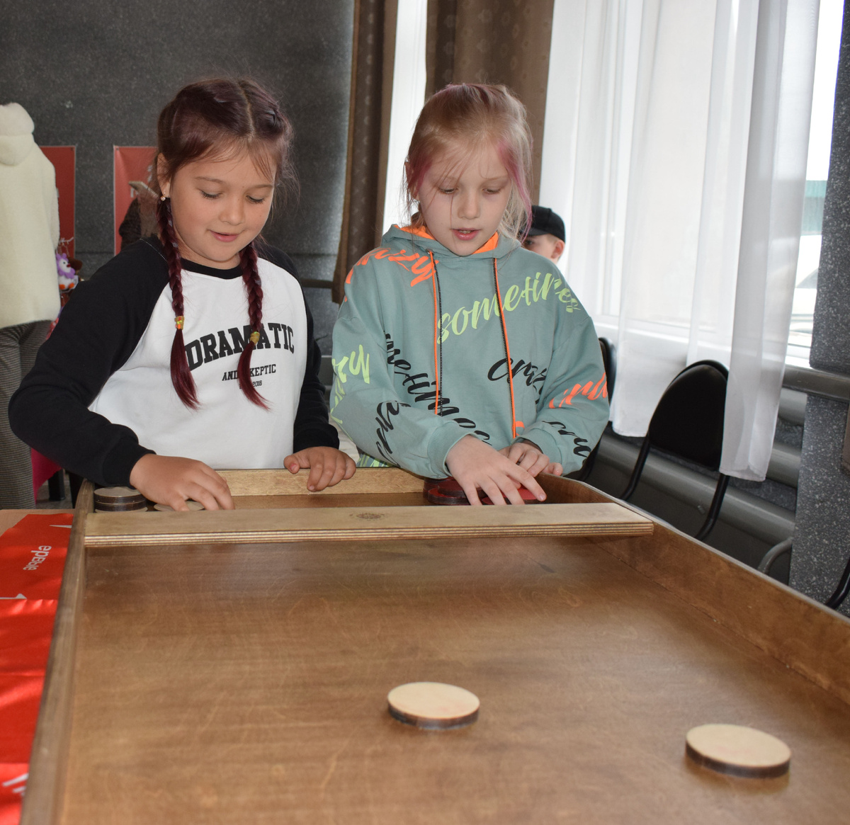 Даша (слева) и Полина Кузьмины играют в игру "Жульбак" на площадке Молодежного центра "Саяны"