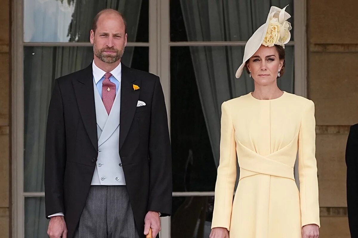    Британские принц Уэльский Уильям и принцесса Уэльская Кэтрин стоят на верхней ступеньке лестницы в саду Букингемского дворца в Лондоне.